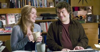 Kate Winslet e Jack Black che sorridono seduti a una scrivania circondati da libri