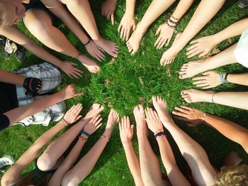 piedi e mani di un cerchio di persone su un prato verde
