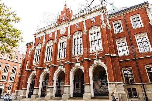 Krakow, Poland - April 24, 2014: Front facade of Collegium Novum - one of the oldest academic buildings of Jagiellonian University in Krakow Poland. There are some people visible walking nearby