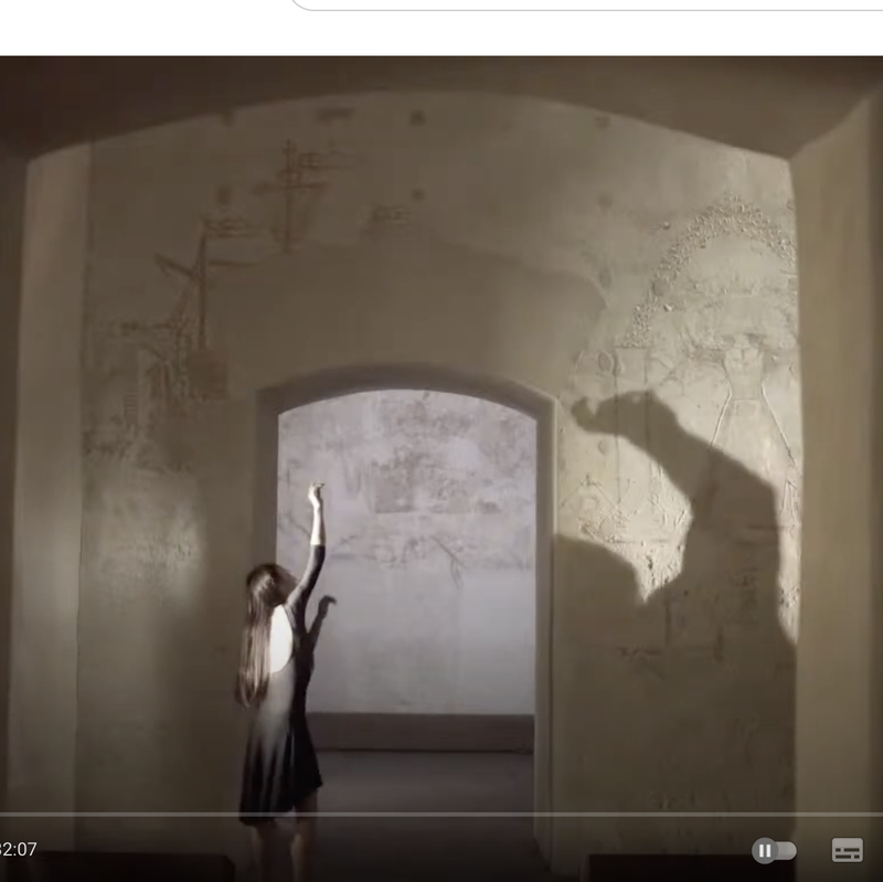 frammento di danza con donna e ombra davanti a scritte sul muro, tratto dal video "Le sciarpe rosse"