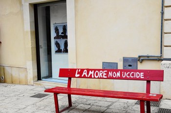 Foto di panchina rossa con la scritta "L'amore non uccide"