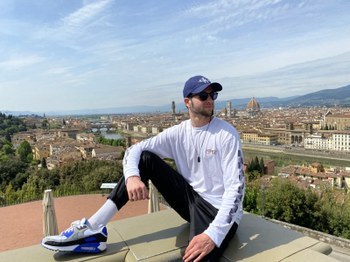 Adrien sitting on a rooftop ovelrooking the city of Florence