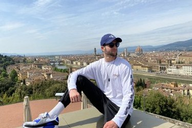 Adrien sitting on a rooftop overlooking the city of Florence