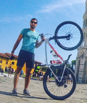 Majid holding his bike in front of the leaning tower of Pisa