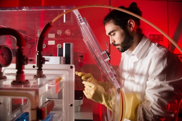 Man with gloves looks at object in his hands. Nano-micro manufacturing laboratory - via Irnerio 46 - Bologna. Year: 2019.