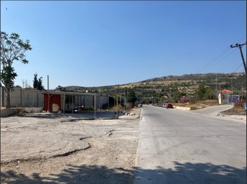 The road that runs alongside the Schistò camp on the outskirts of Piraeus. On the left, the concrete wall surrounding the camp. June 2023