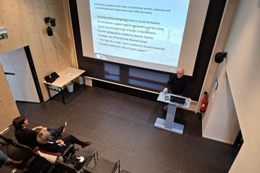 Claudio Minca stands at a lecturn in front of a power point presentation